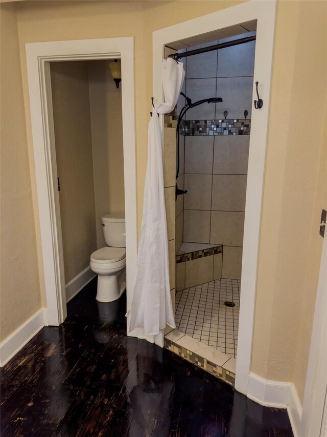 bathroom with hardwood / wood-style flooring, toilet, and a shower with shower curtain