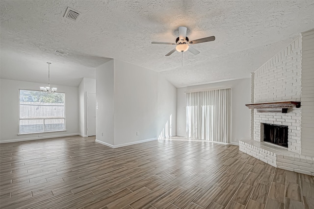 unfurnished living room featuring a fireplace, ceiling fan with notable chandelier, wood-type flooring, and a textured ceiling