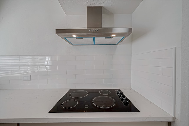 kitchen with light stone countertops, black electric cooktop, and island exhaust hood