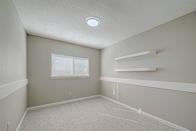 carpeted empty room featuring a textured ceiling