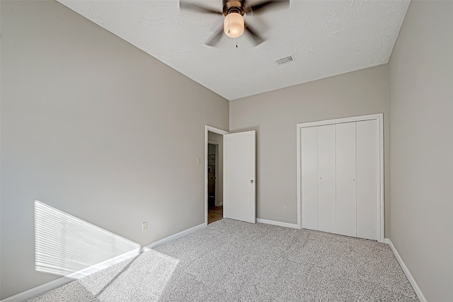 unfurnished bedroom featuring carpet, ceiling fan, a textured ceiling, and a closet