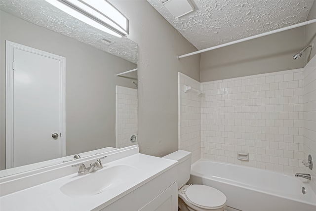 full bathroom with tiled shower / bath, vanity, a textured ceiling, and toilet