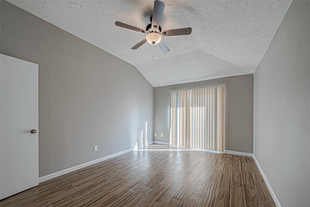 spare room with hardwood / wood-style flooring, a textured ceiling, and vaulted ceiling