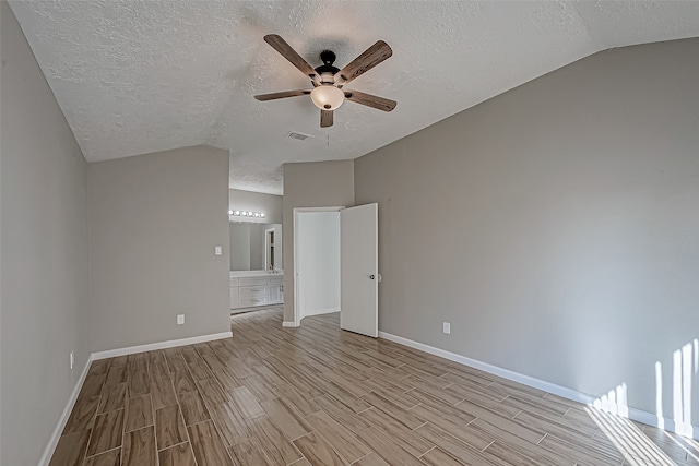 spare room featuring a textured ceiling, light hardwood / wood-style flooring, vaulted ceiling, and ceiling fan