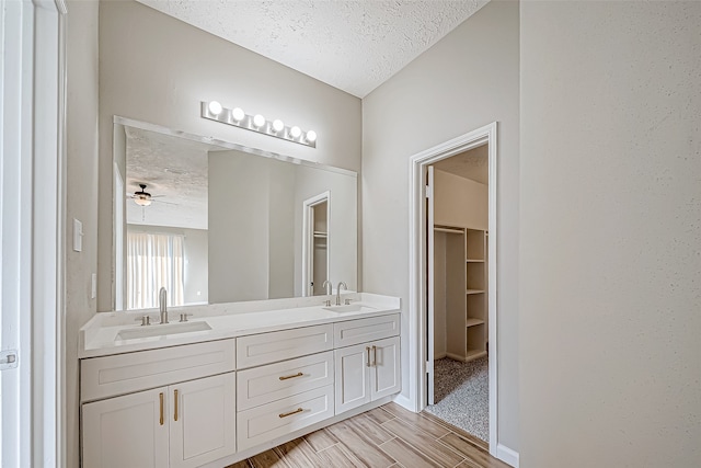 bathroom featuring ceiling fan, vanity, a textured ceiling, and hardwood / wood-style flooring