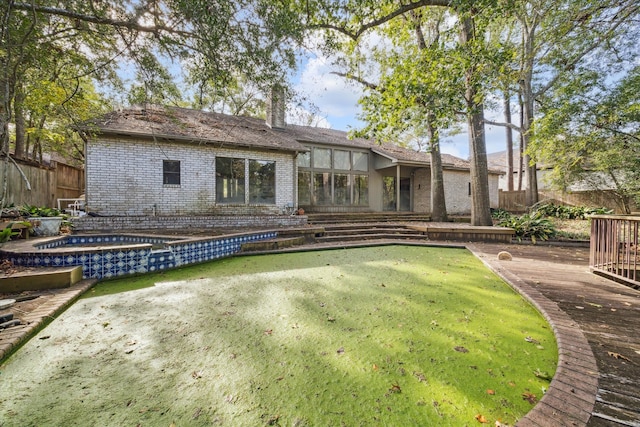 rear view of property featuring an in ground hot tub