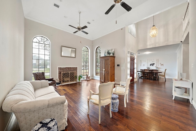 living room featuring a towering ceiling, dark hardwood / wood-style floors, ceiling fan, and crown molding