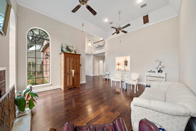 living room with ornamental molding, a towering ceiling, ceiling fan, and dark wood-type flooring