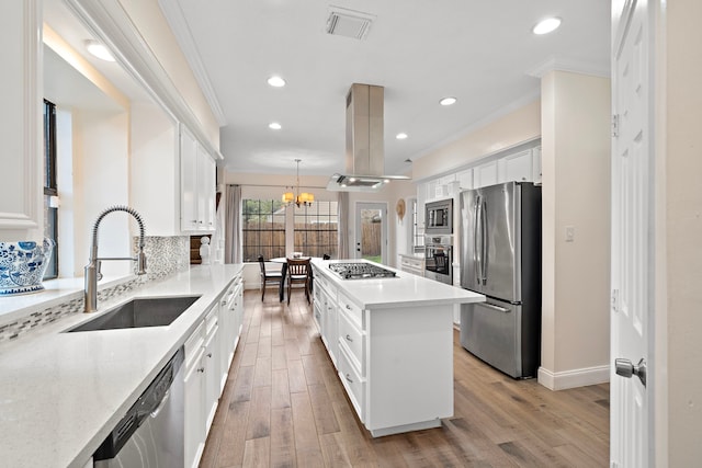 kitchen with appliances with stainless steel finishes, island range hood, sink, white cabinets, and hanging light fixtures