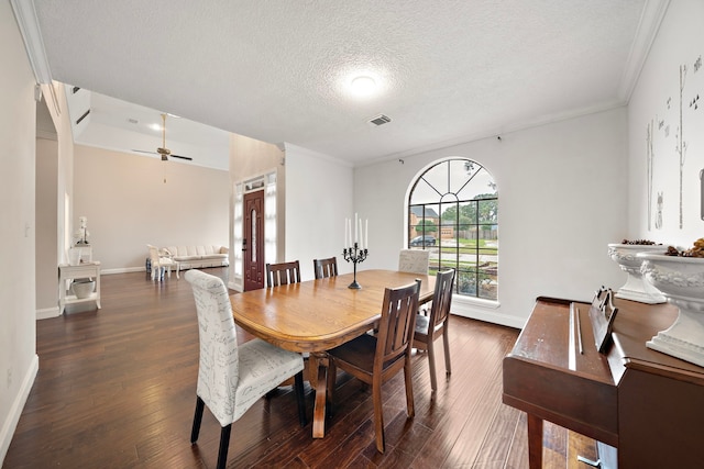 dining room with a textured ceiling, crown molding, ceiling fan, and dark wood-type flooring