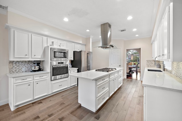 kitchen featuring stainless steel appliances, island range hood, sink, light hardwood / wood-style floors, and white cabinetry