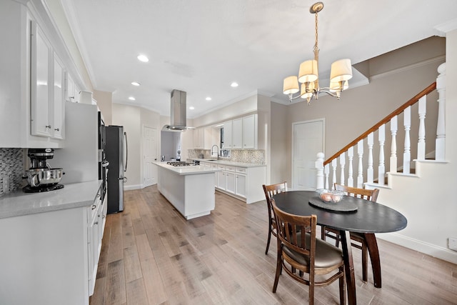 dining space with a notable chandelier, sink, light wood-type flooring, and crown molding