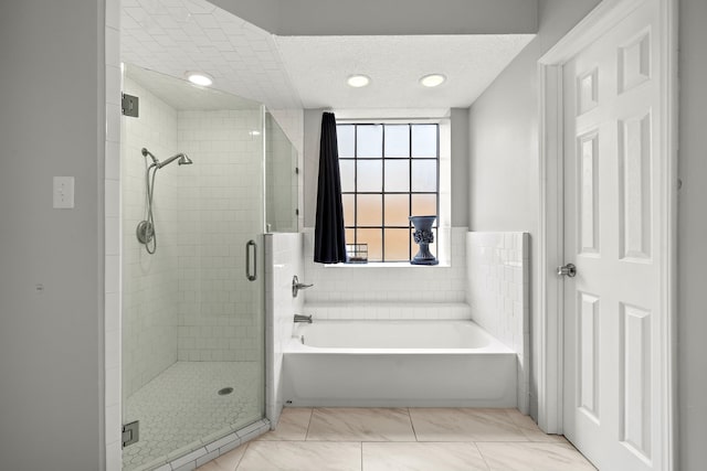 bathroom featuring tile patterned flooring, separate shower and tub, and a textured ceiling