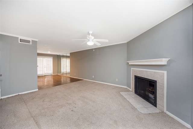 unfurnished living room with a fireplace, light colored carpet, ceiling fan, and crown molding