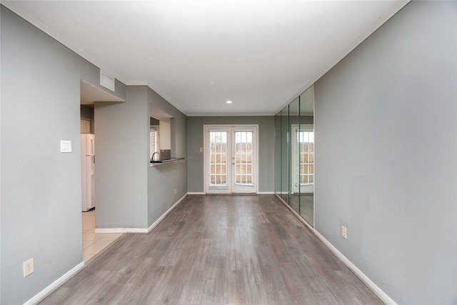 spare room featuring french doors, light hardwood / wood-style floors, and ornamental molding