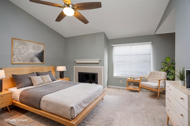 bedroom featuring a tile fireplace, light carpet, ceiling fan, and lofted ceiling