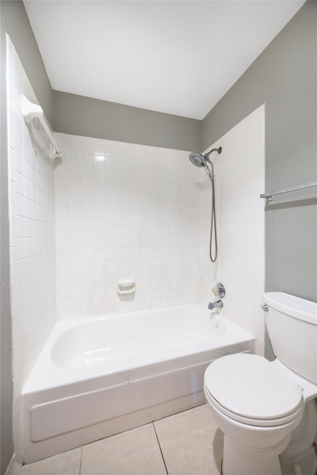 bathroom featuring tile patterned flooring, tiled shower / bath combo, and toilet