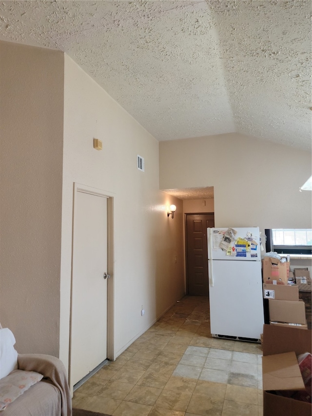 kitchen with a textured ceiling, white fridge, and lofted ceiling