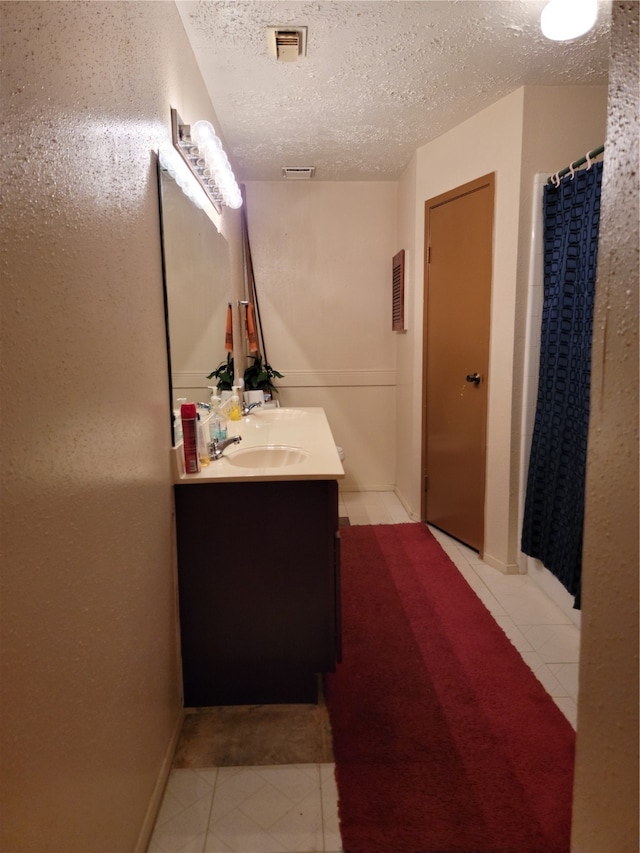 bathroom with vanity, a textured ceiling, and walk in shower