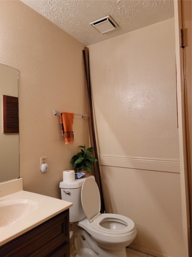 bathroom featuring vanity, toilet, and a textured ceiling