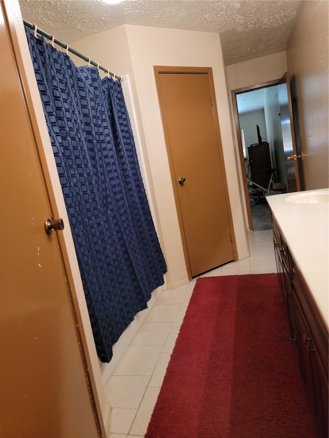 bathroom featuring tile patterned flooring, vanity, and a textured ceiling