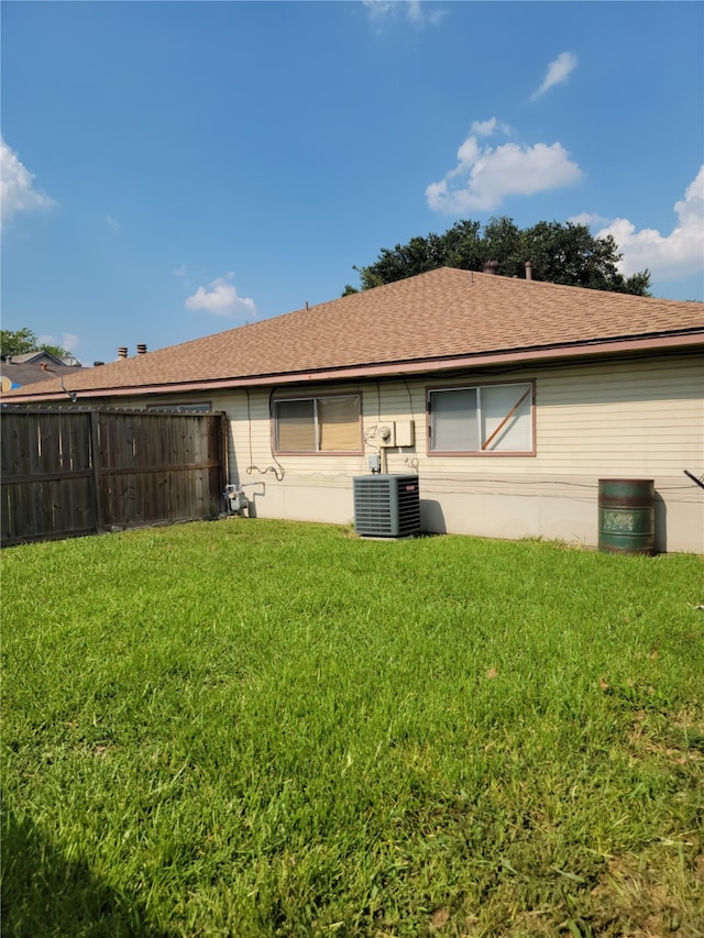 rear view of property with cooling unit and a yard