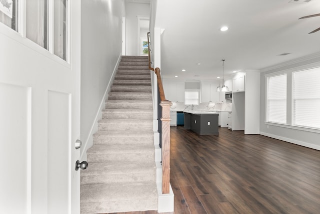 stairs featuring wood-type flooring and crown molding