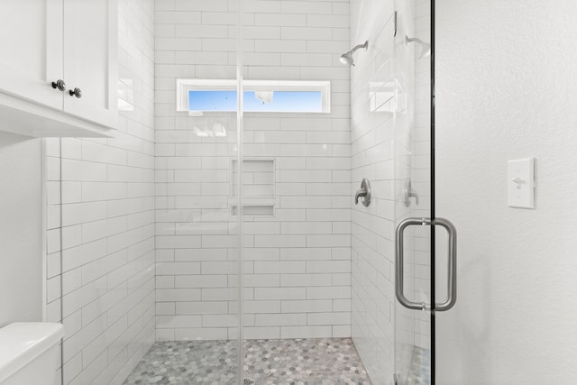 bathroom featuring toilet and a shower with door