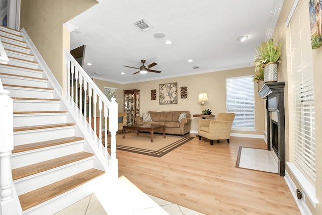 living room with light hardwood / wood-style floors, ceiling fan, and ornamental molding