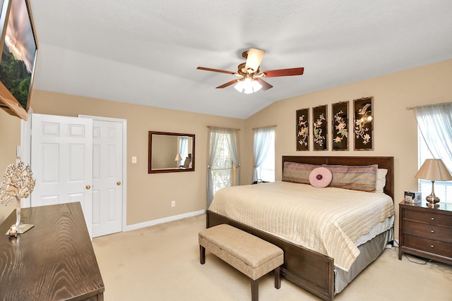 bedroom featuring ceiling fan, vaulted ceiling, light colored carpet, and multiple windows