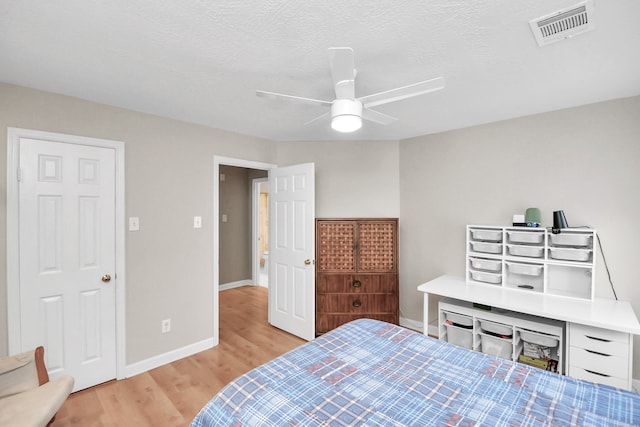 bedroom featuring ceiling fan, light hardwood / wood-style floors, and a textured ceiling