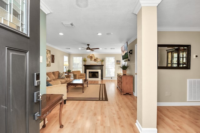 living room featuring light hardwood / wood-style floors, ceiling fan, and crown molding