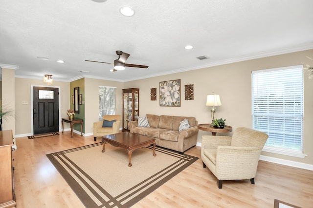 living room featuring a healthy amount of sunlight, light wood-type flooring, and crown molding