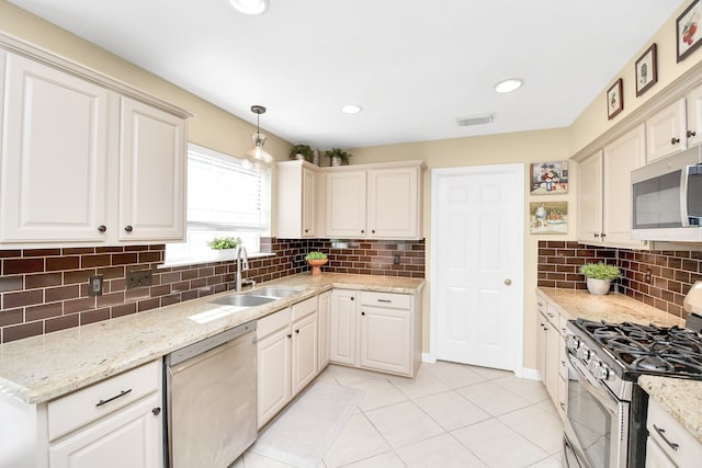 kitchen featuring tasteful backsplash, light stone counters, stainless steel appliances, sink, and hanging light fixtures