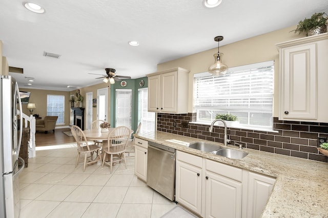 kitchen with ceiling fan, sink, stainless steel appliances, light stone counters, and pendant lighting