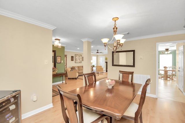 dining room featuring beverage cooler, light hardwood / wood-style flooring, decorative columns, ceiling fan with notable chandelier, and ornamental molding