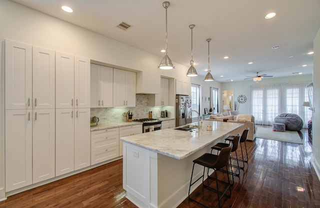 kitchen with ceiling fan, dark wood-type flooring, stainless steel appliances, and decorative light fixtures