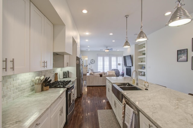 kitchen featuring appliances with stainless steel finishes, dark wood-type flooring, sink, white cabinetry, and hanging light fixtures