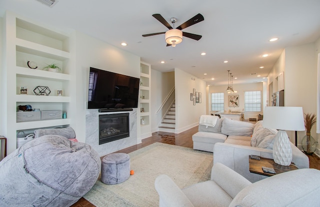 living room featuring hardwood / wood-style flooring, ceiling fan, and built in features