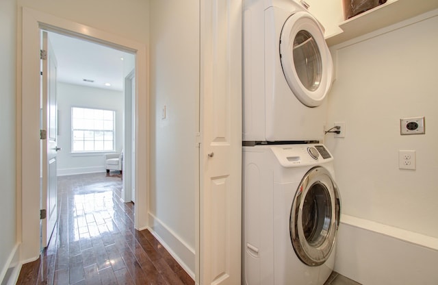 laundry area featuring dark wood-type flooring and stacked washer / drying machine