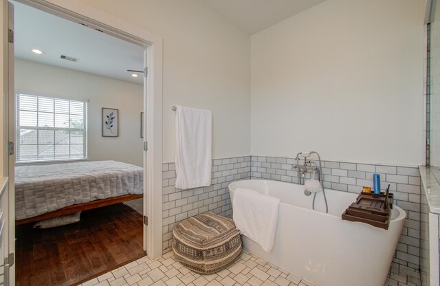 bathroom with a bathtub, hardwood / wood-style flooring, and tile walls