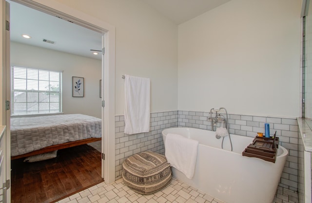 bathroom featuring hardwood / wood-style flooring, a bath, and tile walls