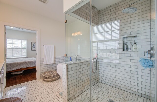 bathroom featuring tile patterned floors, a shower with door, and tile walls