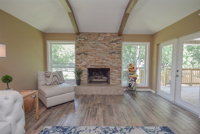 living room featuring beamed ceiling, hardwood / wood-style floors, a stone fireplace, and french doors