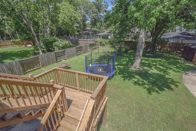 view of yard featuring a trampoline and a wooden deck