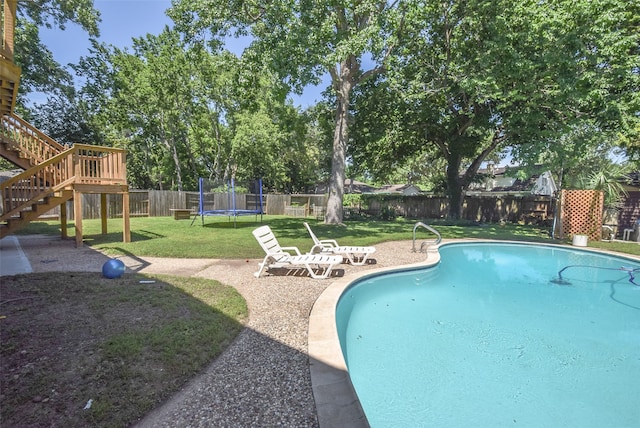 view of swimming pool featuring a trampoline and a yard