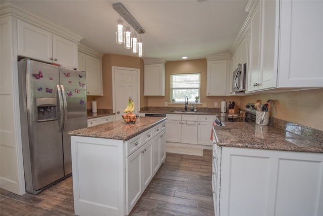 kitchen featuring stainless steel appliances, dark wood-type flooring, sink, pendant lighting, and a center island