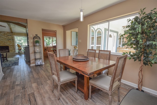 dining area featuring a stone fireplace and dark hardwood / wood-style flooring