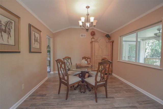 dining space featuring wood-type flooring, an inviting chandelier, vaulted ceiling, and crown molding