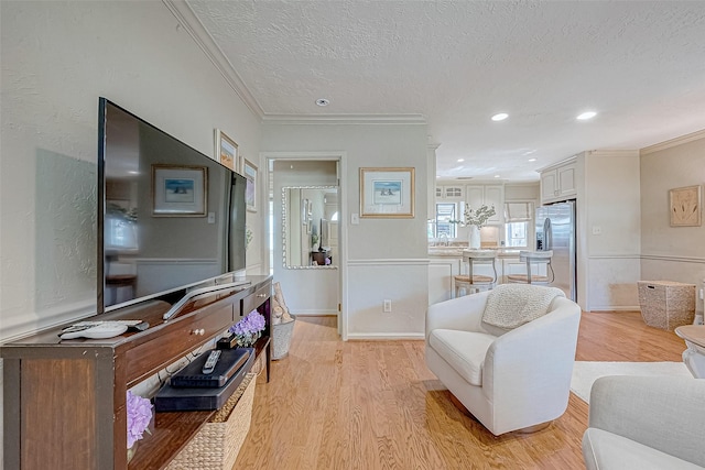 living room featuring ornamental molding, sink, light hardwood / wood-style floors, and a textured ceiling